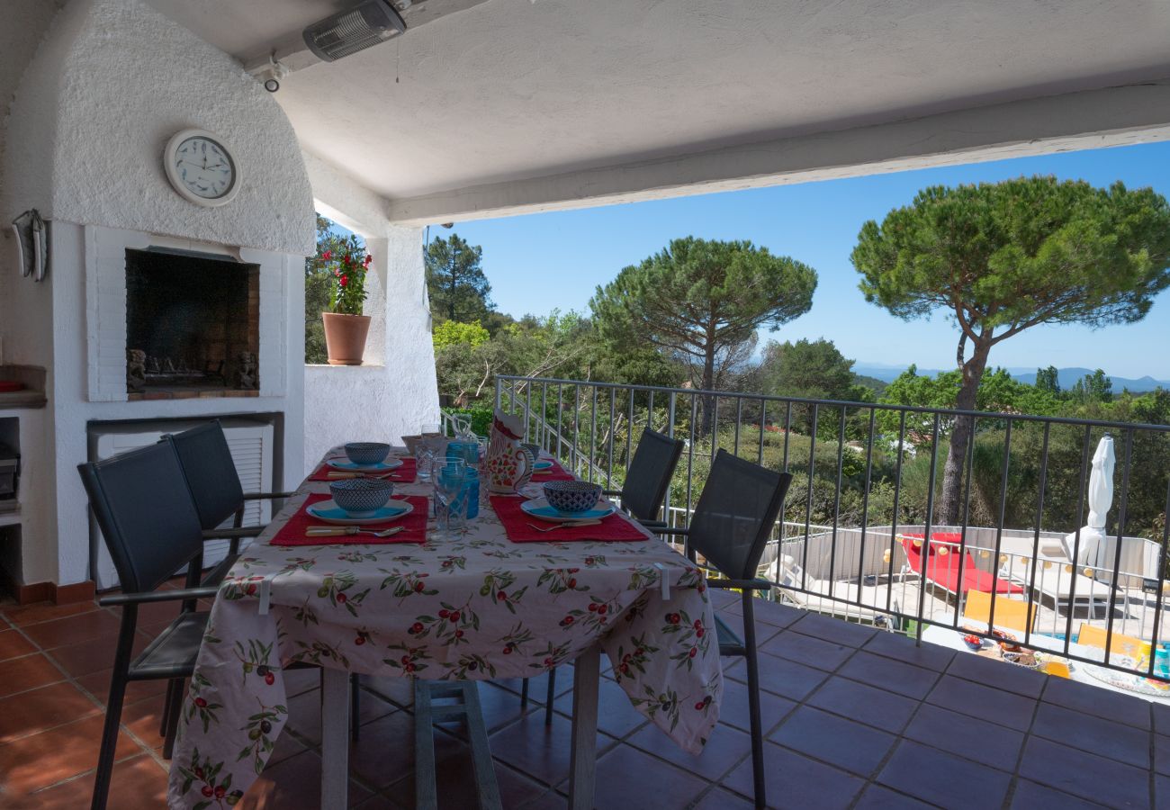 Het overdekte terras van Villa Bellevue, met een eettafel, ingebouwde barbecue en een weids panoramisch uitzicht