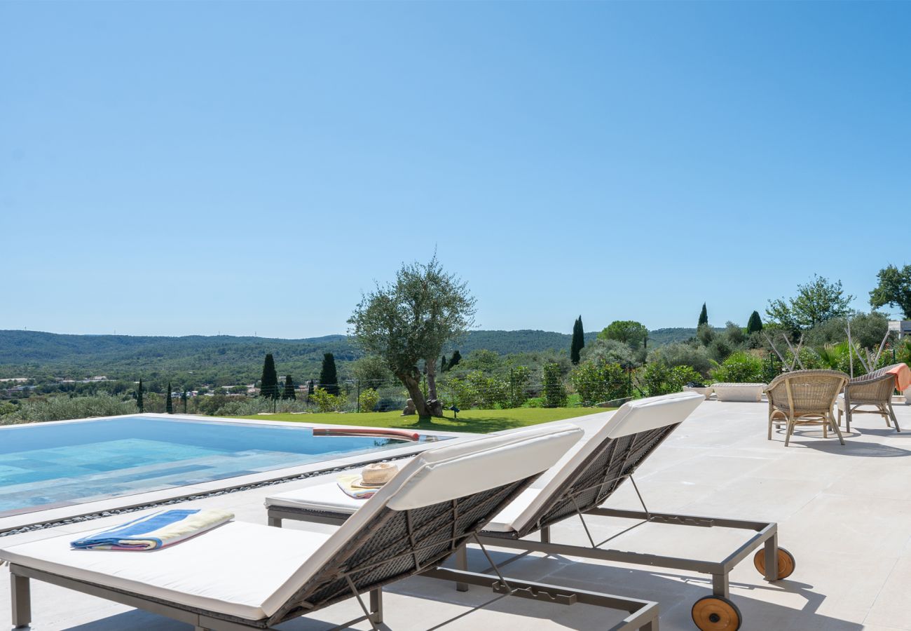 Stijlvol terras met twee ligbedden, rieten stoeltjes en een spiegelzwembad bij Villa Belletoile in de Provence.