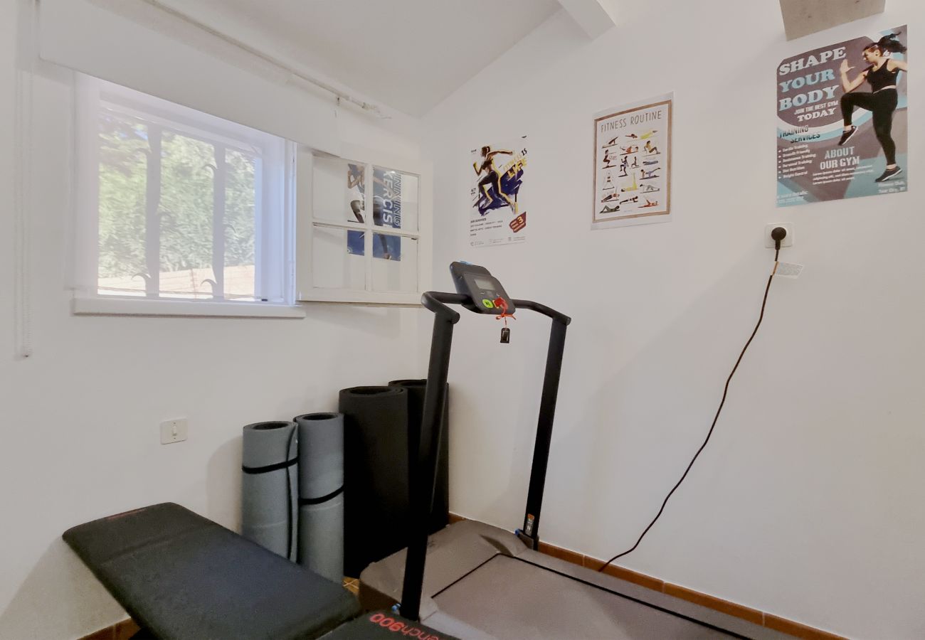 Villa Bellevue's gym, featuring a treadmill, workout bench, and yoga mats